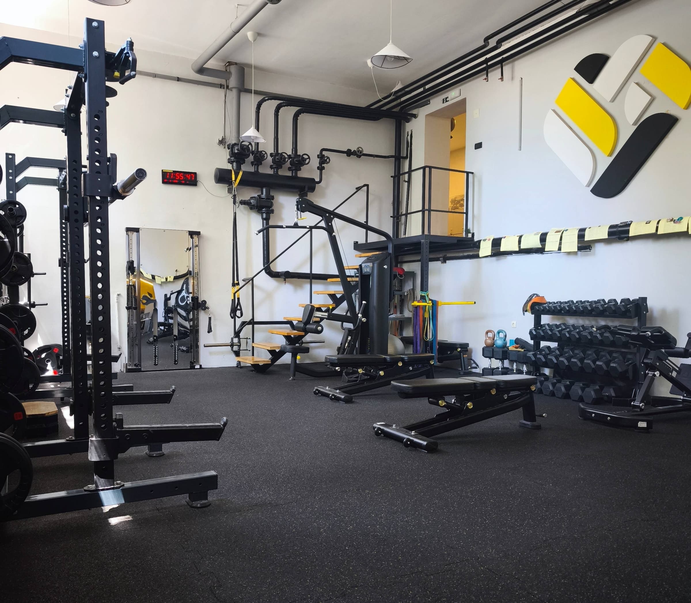 Sala za trening sa stalkom za čučnjeve, klupama i Workout Team logom na zidu